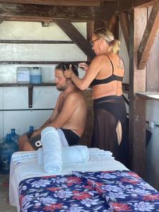 a woman cutting a mans hair in front of a bed at Hotel and Beach Club Escape Holbox in Holbox Island