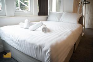 uma cama branca com toalhas e um relógio em - Monthly Stay Offer - en-suite - kitchenette - em Monkwearmouth