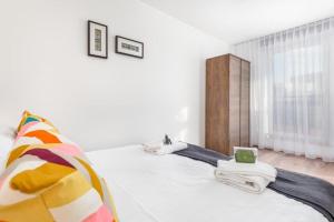 een witte slaapkamer met een bed en een raam bij Modern Riverside Apartment with Free parking space in Szczecin