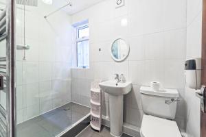a white bathroom with a toilet and a sink at Stunning, large 1 bed riverside flat in London