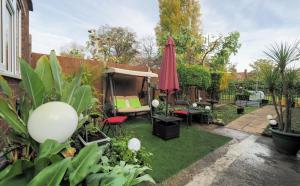 a small garden with a red umbrella and some plants at Stunning, large 1 bed riverside flat in London