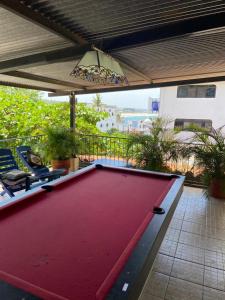 a large red pool table on a patio with two chairs at Hotel & Hostal Mayflower in Puerto Escondido