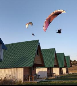 due aquiloni volano nel cielo vicino a un edificio di Vule bungalovi a Žabljak