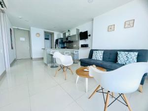 a living room with a blue couch and white chairs at Apartamento Frenta a la Playa in Cartagena de Indias
