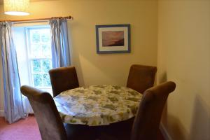 a dining room with a table and chairs and a window at Creran Apartment, Kinlochlaich House in Appin