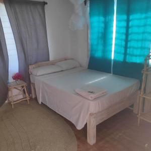 Schlafzimmer mit einem Bett mit weißer Bettwäsche und einem Fenster in der Unterkunft Sunny garden rooms Watamu in Watamu