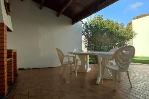 Una mesa blanca y sillas en un patio. en Villa maraichine rénovée, grand jardin et wifi, entre Plage et Marché, en Saint Gilles Croix de vie
