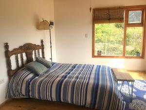 1 cama con edredón de rayas azul y blanco en un dormitorio en Casa luminosa y confortable rodeada de naturaleza en San Carlos de Bariloche