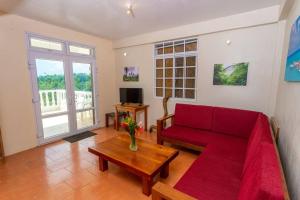 ein Wohnzimmer mit einem roten Sofa und einem Tisch in der Unterkunft Oceanfront 3-bedroom villa with spectacular view! in Calibishie