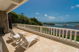 two chairs and a table on a balcony with the ocean at Oceanfront 3-bedroom villa with spectacular view! in Calibishie