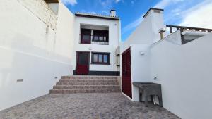 uma casa branca com uma porta vermelha e escadas em Santa Luzia Apt I em Ribeira Grande