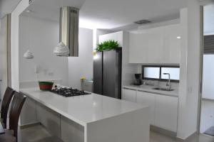 a kitchen with a black refrigerator and white cabinets at Apartamento Samaria Club De Playa in Santa Marta