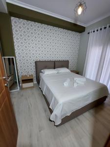 een slaapkamer met een groot bed met witte lakens bij Vila Tafa apartments ap3 in Tirana