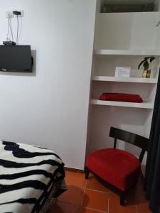 una camera con un letto e una sedia rossa di Patry's Cottage a Puerto Iguazú