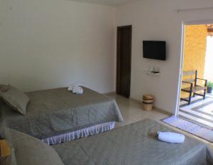 een hotelkamer met 2 bedden en een televisie bij Pousada Viva Barra in Barra Grande