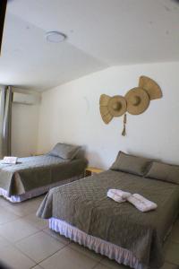 een slaapkamer met 2 bedden en een ventilator aan de muur bij Pousada Viva Barra in Barra Grande