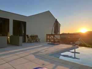 a house with a swimming pool and the sunset at DouroXisto in Peso da Régua