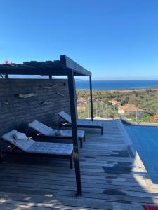una terraza con tumbonas y vistas al océano. en Modern house with private pool and stunning view 800m from beach., en Sagone