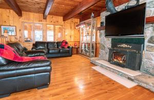 sala de estar con muebles de cuero y chimenea en Pine Springs Retreat with Hot Tub Steam Room Lake Kushog, en Algonquin Highlands