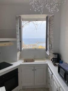 a kitchen with a sink and a large window at Côté Vieux Port in Bastia