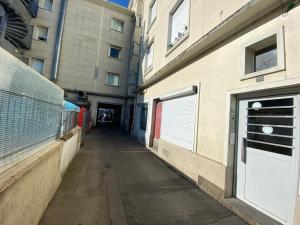 un callejón entre dos edificios con puertas blancas de garaje en Splendide studio Cosy à Caen gare, en Caen
