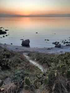 una puesta de sol sobre el océano con una playa rocosa en Gli Appartamenti degli Dei, en Milazzo