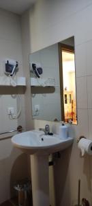 ein Badezimmer mit einem weißen Waschbecken und einem Spiegel in der Unterkunft Alojamientos Puerta del Parque in Cazorla
