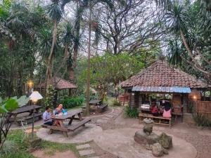 Un groupe de personnes assises à une table de pique-nique dans un parc dans l'établissement Grand Mulia Sakinah Resort & Outbond, à Pasuruan