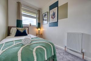 1 dormitorio con 1 cama con manta verde y ventana en 3 bedrooms, garden, free parking en Cirencester