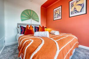 Un dormitorio con una pared de color naranja y una cama en 3 bedrooms, garden, free parking en Cirencester