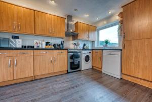 cocina con armarios de madera, lavadora y secadora en 3 bedrooms, garden, free parking en Cirencester