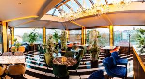 a restaurant with tables and chairs and a chandelier at Lion's Hotel in Chişinău