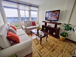 sala de estar con sofá blanco y TV en Cómodo, amplio y céntrico apartamento en Sopocachi, en La Paz