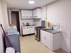 a kitchen with white cabinets and a stove top oven at Cómodo, amplio y céntrico apartamento en Sopocachi in La Paz