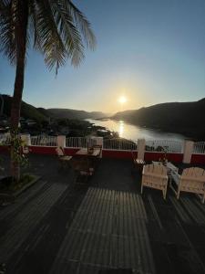 una terrazza con tavoli e sedie e vista sull'acqua di Pousada Maria Bonita - Piranhas, Alagoas. a Piranhas