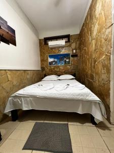 uma cama num quarto com uma parede de pedra em Pousada Ilha Grande em Abraão