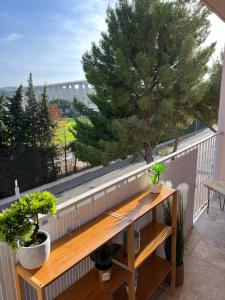 マルティーグにあるLE PARADIS APPARTEMENTの木製ベンチと木が備わるバルコニー