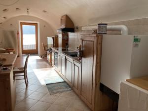a kitchen with a refrigerator and a table in it at CASA DIAF appartamento incantevole Carano Ville di Fiemme in Carano