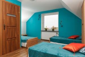 a blue room with two beds and a window at Hotelik Bach in Gdańsk