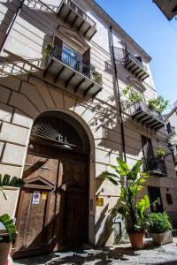 a building with a wooden door and a balcony at Dimora Sinibaldi in Palermo