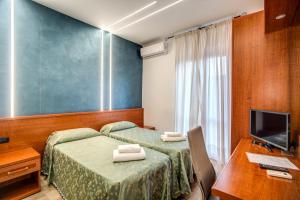 Habitación de hotel con 2 camas, escritorio y TV. en Hotel Millerose, en Roma