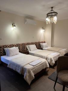 three beds in a hotel room with a chandelier at Bedouin Pyramids View in Cairo