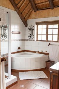 baño con una gran bañera blanca y ventana en Hotel Nomad Belvedere Lodge, en Midrand