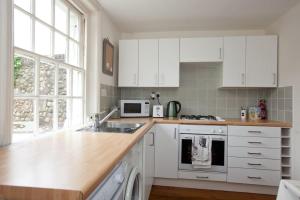 a kitchen with white cabinets and a sink at Quaker Cottage in historic Arundel in Arundel