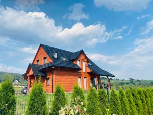 a wooden house with a black roof at Scenic Chalet Malowniczy Domek in Szlembark
