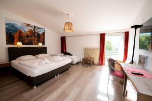 a bedroom with two beds and a desk and window at Parkhotel Zur Linde in Silandro