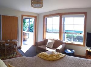 a bedroom with a bed and a couch and windows at Rarangi Seaview On the Beach B&B in Blenheim
