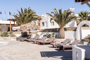 a row of chaise lounges and palm trees at a resort at Happy Apartments Mykonos in Klouvas