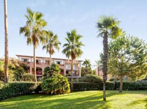 a building with palm trees in front of a yard at Superbe Appartement à 50 m de la mer in Hyères