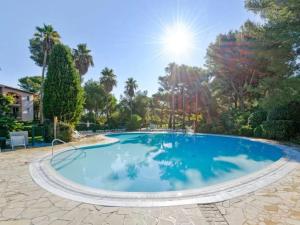 a large swimming pool in a yard with trees at Superbe Appartement à 50 m de la mer in Hyères +11 photos